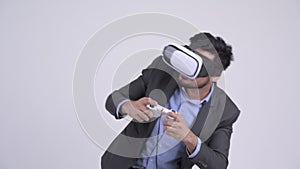 Young bearded Indian businessman playing games and using virtual reality headset