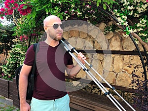 A young bearded male photographer with a tripod in his hand is walking in Antalya old town Kaleici. Horizontal image