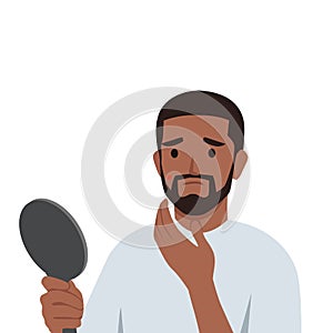 Young bearded man with acne problem looking in mirror