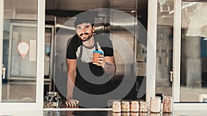 Young Bearded Man in Apron Standing in Food Truck.