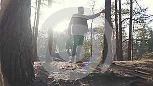 Young bearded man with an axe walk in forest and cuting a tree. Unshaven forester with an ax outdoors.