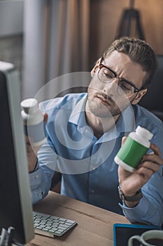 Young bearded man in blue shirt reading about vitamins