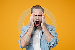 Young bearded man in casual blue shirt posing isolated on yellow orange background studio portrait. People lifestyle