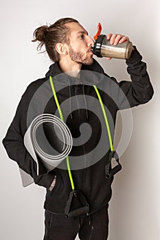 A young bearded man drinking a protein shake after working out. Exercise, healthy living, keeping fit concept