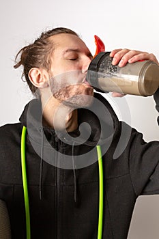 A young bearded man drinking a protein shake after working out. Exercise, healthy living, keeping fit concept