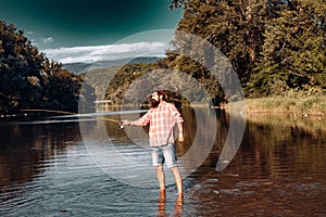 Young bearded man fishing. Man fly fishing. Weekend time. Happy fisherman. In river or on the lake. Fishing skills