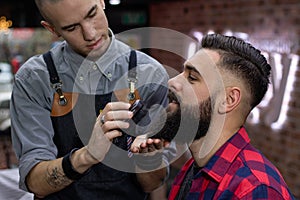 Young bearded man getting a royal treatment in barber shop.