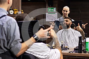 Young bearded man getting shaved in barber shop.