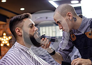 Young bearded man getting shaved in barber shop.