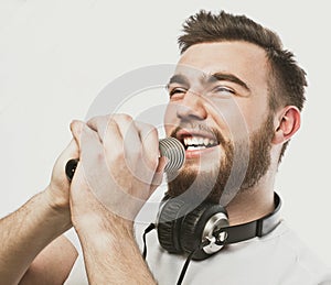 Young bearded man with headphones and microphone over white background