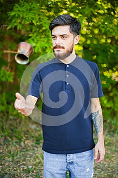 Young bearded man juggles with the coffee kettle.
