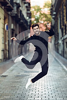 Young bearded man jumping in urban street wearing casual clothes