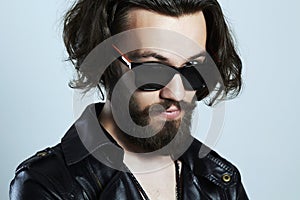 Young bearded man in a leather. Hipster in sunglasses