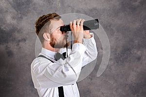 Young bearded man looking through a binoculars