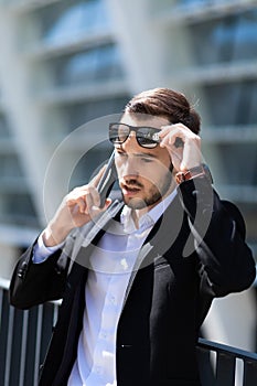 Young bearded man with phone stunned by unexpected news. Shocked reaction, surprise