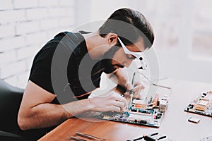 Young Bearded Man Repairing Motherboard from PC.