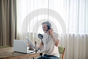 Young bearded man sitting in headphones and speaking in microphone