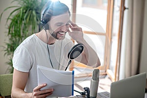 Young bearded man sitting in headphones and speaking in microphone