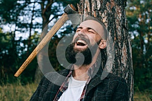 Young bearded man smiling widely in the woods outdoors. Happy man
