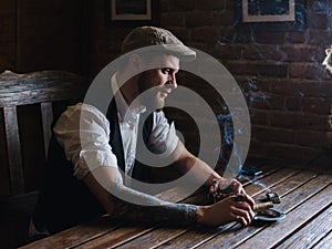 A young bearded man smoking a cigar in a pub