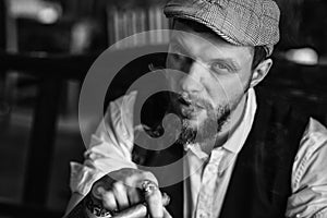 A young bearded man smoking a cigar in a pub