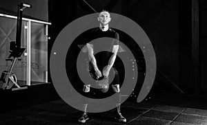 Young bearded man in sportswear working out with kettle bell.