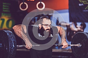 Young bearded man straining to lift heavy weights during a workout session in a gym