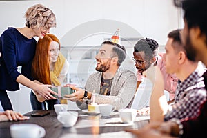 Young bearded man wearing bithday cap getting pleasant gift