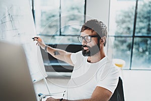 Young bearded man wearing eye glasses and working at sunny office.Blurred background. Horizontal. Cropped.