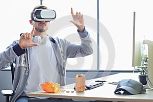 Young bearded man wearing virtual reality glasses in modern interior design coworking studio