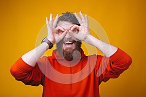 Young bearded man on yellow background excited keeping ok gesture on eye...