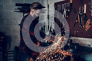 Young Bearded Mechanic Repairing Parts in Garage.