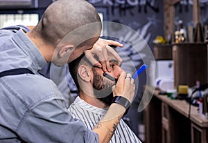 Beard and sideburns shaving and shaping with vintage straight razor. photo