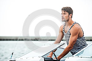 Young bearded sailor man driving his motor boat