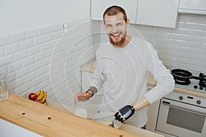 Young bearded smiling guy with artificial limb  cooks in the kitchen
