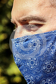 Young bearded white man with a blue fabric face mask during pandemic; COVID-19 outbreak. Prevent the flu