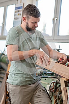 Young bearded worker in a carpenter`s workshop using grinding machine