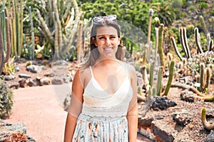 Young beatiful woman smiling happy and cheerful at green cactus park on a sunny day of summer