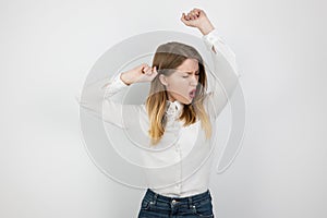 Young beatuiful blond woman dancing in winning position clenching her fists looking happy on isolated white background, body