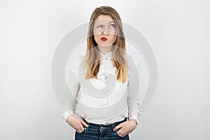 Young beatuiful blond woman looks hesitant standing on isolated white background, body language