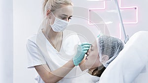 The young beautician doctor preparing to making injection in female forehead. The doctor cosmetologist makes anti-aging treatment