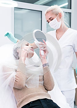 The young beautician doctor preparing to making injection in female lips. The doctor cosmetologist makes lip augmentation