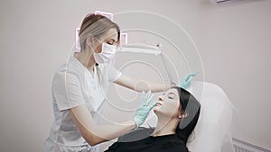 The young beautician doctor preparing to making injection in female lips. The doctor cosmetologist makes lip augmentation procedur