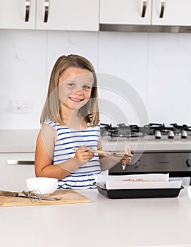 Young beautiful and adorable girl 6 or 7 years old cooking and baking at home kitchen preparing chocholate cake smiling happy and