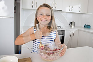 Young beautiful and adorable girl 6 or 7 years old cooking and baking at home kitchen preparing strawberry cake with bowl smiling