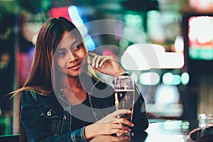 Young beautiful adult girl in a club drinking beer alone