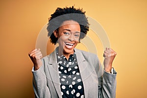 Young beautiful African American afro businesswoman with curly hair wearing jacket celebrating surprised and amazed for success