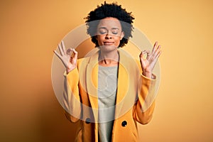 Young beautiful African American afro businesswoman with curly hair wearing yellow jacket relax and smiling with eyes closed doing