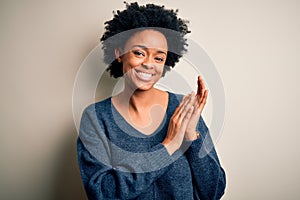 Young beautiful African American afro woman with curly hair wearing casual sweater clapping and applauding happy and joyful,