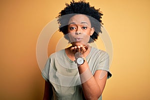 Young beautiful African American afro woman with curly hair wearing casual t-shirt looking at the camera blowing a kiss with hand